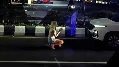 Seorang perempuan warga negara asing terlihat berlutut di depan mobil di Jalan Tugu Ngurah Rai, Nusa Dua, Badung, Kamis (21/5/2026) malam. (dok. tangkapan layar akun instagram @denpasarviralcom)