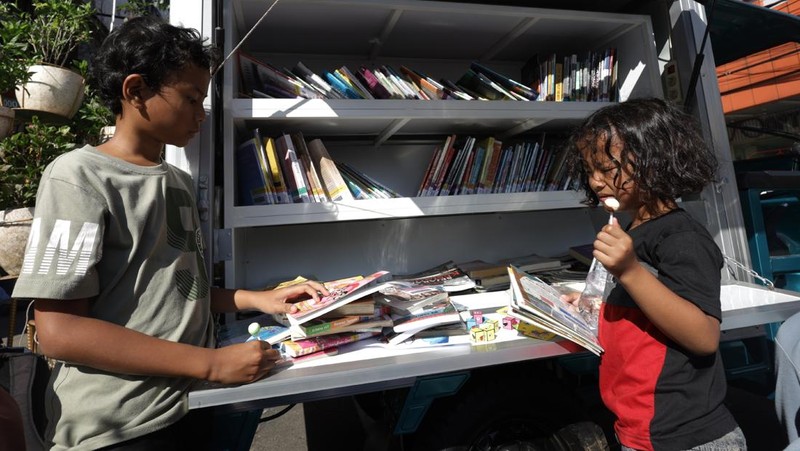 Sejumlah anak dan orang dewasa membaca buku di perpustakaan keliling di Kediri, Jawa Timur, Minggu (24/5/2026). Dinas Pemberdayaan Perempuan dan Perlindungan Anak Kota Kediri bersama Forum Anak Kota Kediri menyelenggarakan layanan perpustakaan keliling pada minggu keempat setiap bulan untuk meningkatkan minat baca, menyosialisasikan hak-hak anak, membangun kesadaran bahaya pernikahan dini, putus sekolah, dan perundungan, serta mendukung implementasi PP Tunas sebagai perlindungan anak di ruang digital. ANTARA FOTO/Prasetia Fauzani