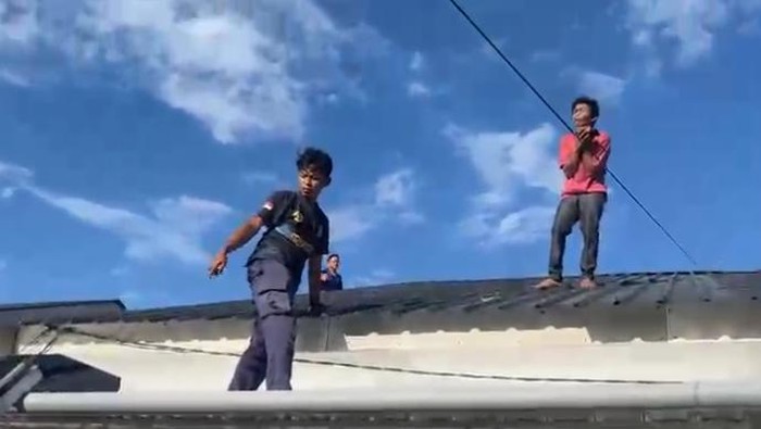 Petugas Damkar Parepare mengevakuasi pemuda yang terjebak di atap rumah.