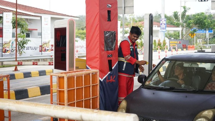 Petugas tol sedang melayani pengendara yang melintas