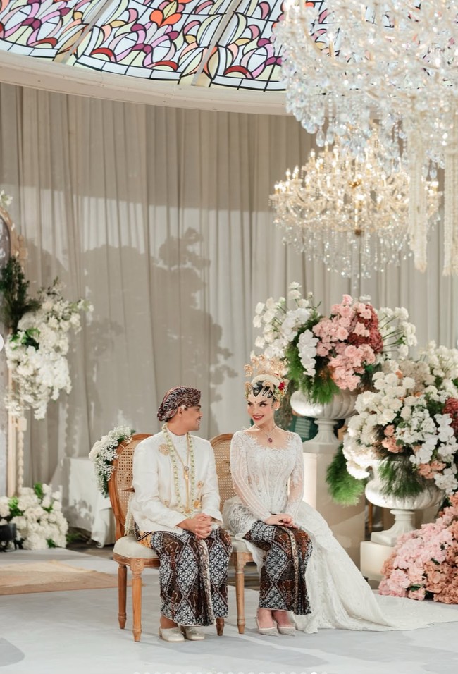 Suasana akad terlihat begitu sakral dengan dominasi warna putih dan krem. Dekorasi bunga putih dan sentuhan pastel pink mempermanis area pelaminan tanpa terlihat berlebihan. Foto: Instagram/@tengkunadiraadn