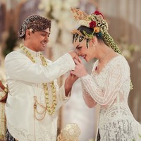 Agassi Revano tampil gagah mengenakan beskap putih beraksen bordir dan payet berkilau. Ia memadukannya dengan kain batik bernuansa cokelat gelap khas Yogyakarta. Detail kalung melati, keris, serta aksesori rantai emas pada beskap menambah kesan tradisional. Foto: Instagram/@tengkunadiraadn