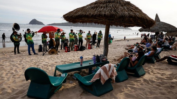 Suasana pantai di Mazatlan, Meksiko, dipenuhi nuansa hangat dan meriah saat sebuah band asal Sinaloa tampil menghibur wisatawan yang menikmati matahari terbenam, Minggu (24/5/2026). Alunan musik khas daerah berpadu dengan panorama senja menciptakan daya tarik tersendiri bagi para pengunjung yang memadati kawasan pantai. REUTERS/Daniel Becerril