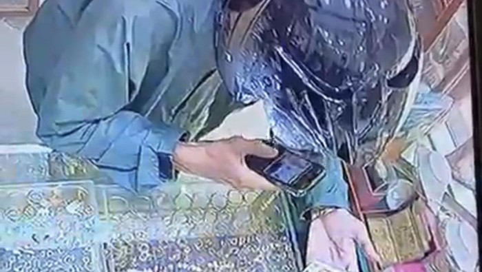 Pelaku sedang memoto emas milik toko di Medan sebelum dibawa kabur. (dok. Langkapan layar cctv)