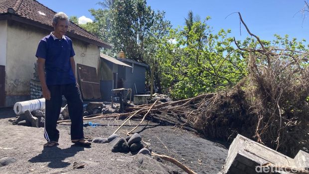 Wayan Galung (52), warga pesisir Monggalan, Desa Kusamba, Kecamatan Dawan, Klungkung, Bali tengah memandang pekarangan depan rumahnya yang sudah habis dilahap abrasi, Senin (25/5/2026). (Fatih Kudus Jaelani/detikBali). Wayan Galung (52), warga pesisir Monggalan, Desa Kusamba, Kecamatan Dawan, Klungkung, Bali tengah memandang pekarangan depan rumahnya yang sudah habis dilahap abrasi, Senin (25/5/2026). (Fatih Kudus Jaelani/detikBali).