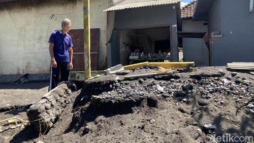 Wayan Galung (52), warga pesisir Monggalan, Desa Kusamba, Kecamatan Dawan, Klungkung, Bali tengah memandang pekarangan depan rumahnya yang sudah habis dilahap abrasi, Senin (25/5/2026). (Fatih Kudus Jaelani/detikBali).