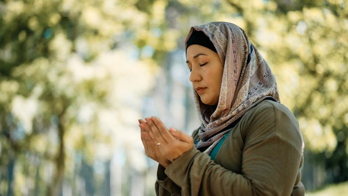 Religious Middle Eastern woman praying while being in the park. Copy space.