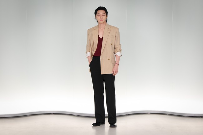 Park Seo Joon tampil beda dengan atasan merah berkerah V dibalut blazer berwarna krem. Sang aktor memancarkan karismanya dengan sleek back hair, yang mengekspos bagian dahinya. Foto: Getty Images