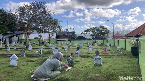 Seorang peziarah menaburkan bunga di pusara keluarganya, di pemakaman kampung islam Lebah, Klungkung, Bali, Rabu (27/5/2026).
