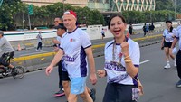 Ayu bersama dengan peserta lari lainnya memakai jersey bernuansa putih. Ayu yang memakai celana panjanghitam tersenyum ke arah kamera sambil berlari. Pada momen itu ada tiga kategori lari, 5K putra, 5K putri, dan 10K umum. Foto: Instagram @ayukhadijahazhari