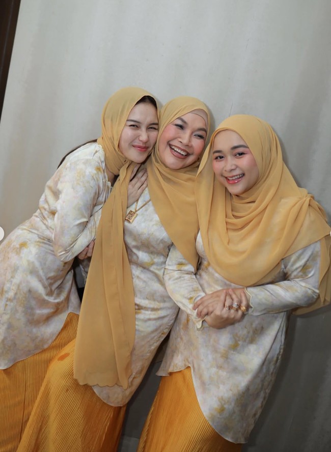 Sementara para wanita mengenakan baju kurung modern berpotongan longgar. Bagian bawahnya dipadukan dengan rok plisket warna mustard. Kerudung polos senada juga tampak membungkus kepala Ayu, Umi Kalsum, dan Syifa. Foto: Instagram/@ayutingting92