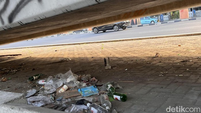 Sampah plastik dan botol miras berserakan di kolong Tol Pettarani, Makassar.