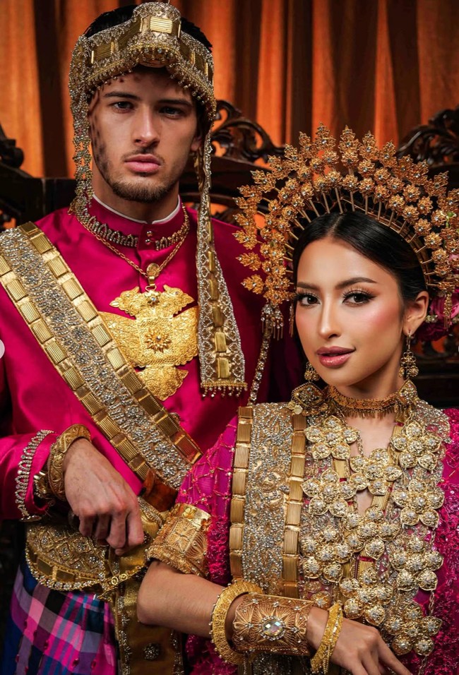 Jennifer Coppen dan Justin Hubner tampil kompak mengenakan baju Bodo bernuansa pink fuchsia yang mencolok. Busananya dipenuhi detail payet dan bordir emas yang sangat ramai, memberi kesan royal bak pengantin kerajaan tradisional. Foto: Instagram/@jennifercoppenreal20