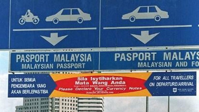 A sign board displayed on the causeway leading to Johor Bahru, one of Malaysias immigration checkpoints, warns travellers to declare the amount of currency and travellers cheques they are carrying in and out of Malaysia 30 September. The new curren