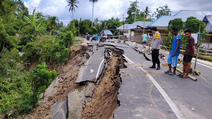 Jalan di Kecamatan Pulubala, Gorontalo, amblas akibat longsor, nyaris putus. Hanya kendaraan roda dua yang bisa melintas.