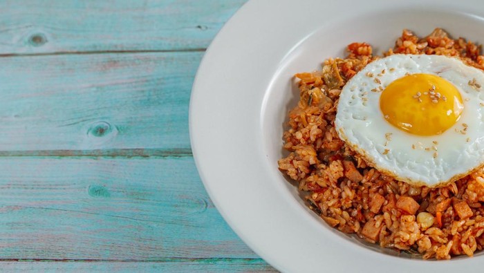 Korean food kimchi fried rice dish with fried egg on white plate