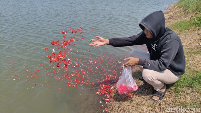 Ferry (23) saat menaburkan bunga dari tanggul Lumpur Lapindo