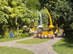 Pengunjung berdoa di Pura Taman Magenda, Gianyar, Bali. Tempat ibadah tersebut berdampingan dengan air terjun dan kolam alami. Pemedek cukup membayar punia (donasi) jika hendak berdoa maupun melukat di Pura Taman Magenda.