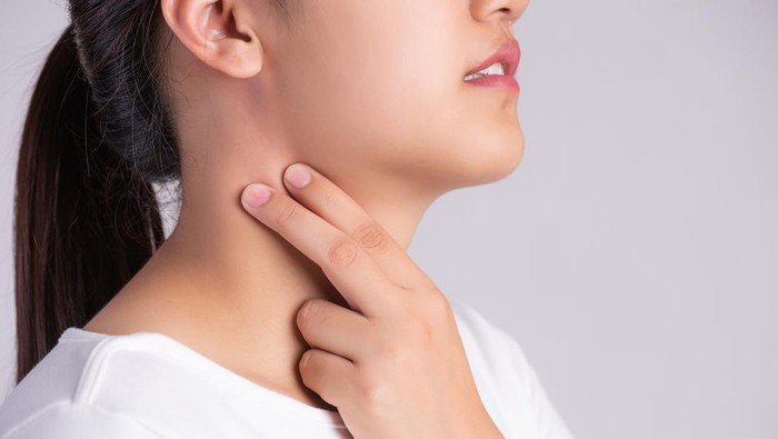 Sore Throat. Closeup Of Beautiful Young Woman Hand Touching Her Ill Neck. Healthcare and medical concept.