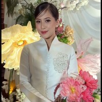 Kebaya putih datang dari koleksi Laviena Wedding Gallery. Kebaya kerah tinggi tampak manis berkat aksen mawar berpayet, berpadu apik dengan rok panjang berhias ratusan aplikasi bunga. Foto: Instagram/@anandachrstie