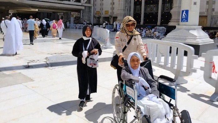 Petugas haji membantu mendorong kursi roda Kurnifati dari Masjidil Haram ke terminal bus.