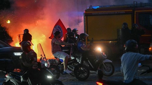 PSG supporters drive their scooters past anti-riot police officers (Rear L and R) as they celebrate their teams win in the UEFA Champions League final between Paris Saint-Germain (PSG) and Arsenal FC played in Budapest, at Place du Trocadero in Paris on May 30, 2026. (Photo by LOU BENOIST / AFP)