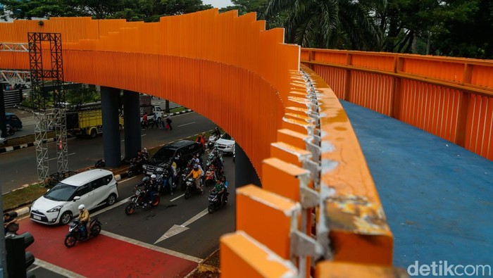 Seorang penjual balon melintas di samping Skywalk Tegar Beriman, Cibinong, Kabupaten Bogor, Senin (1/6/2026). Jembatan penyeberangan orang (JPO) tersebut kini menjadi ikon modern terbaru di kawasan tersebut.