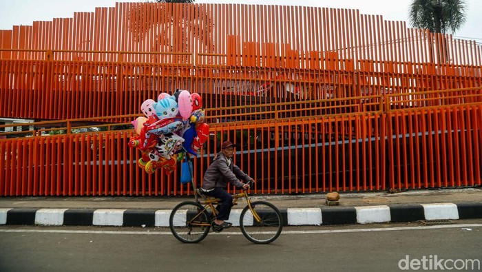 Seorang penjual balon melintas di samping Skywalk Tegar Beriman, Cibinong, Kabupaten Bogor, Senin (1/6/2026). Jembatan penyeberangan orang (JPO) tersebut kini menjadi ikon modern terbaru di kawasan tersebut.