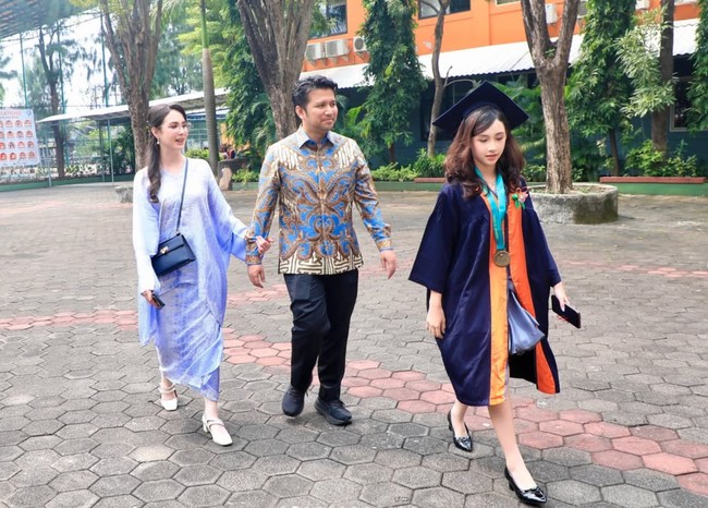 Arumi dan suaminya tampil kompak kenakan batik. Sementara sang putri, Lakeisha mengenakan jubah serta topi toga kelulusan. Foto: Instagram/@arumibachsin_94