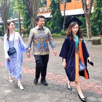 Arumi dan suaminya tampil kompak kenakan batik. Sementara sang putri, Lakeisha mengenakan jubah serta topi toga kelulusan. Foto: Instagram/@arumibachsin_94