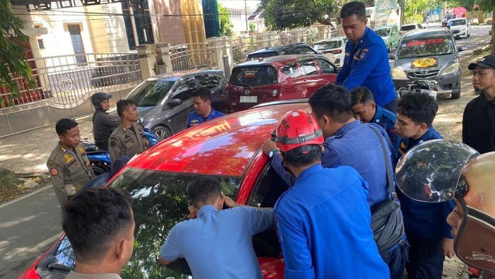 Personel Damkar Bone saat melakukan penyelamatan balita terkunci di dalam mobil.