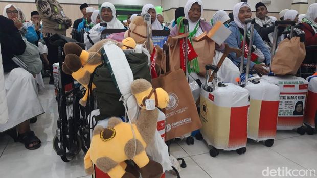 Jemaah haji Kloter 1 asal.Tegal menunjukkan oleh-oleh boneka unta untuk anak cucunya.