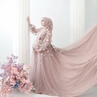 Pilihan gaya hijab yang diikatkan rapi ke belakang dipadukan dengan gaun berpotongan longgar di bagian perut ini berhasil memberikan kesan anggun, pas dengan latar belakang dekorasi mawar merah muda dan biru yang estetis. Foto: Dok. Instagram @dinanfajrina.