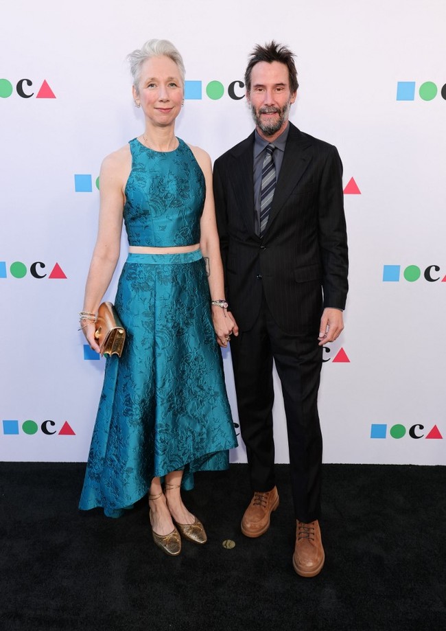 Dalam momen tersebut, Keanu tampil mengenakan setelan jas hitam. Sementara itu, Alexandra atasan warna hijau yang senada dengan roknya. Keduanya tampil mesra dengan saling bergandengan tangan di karpet merah Foto: Getty Images via AFP/EMMA MCINTYRE