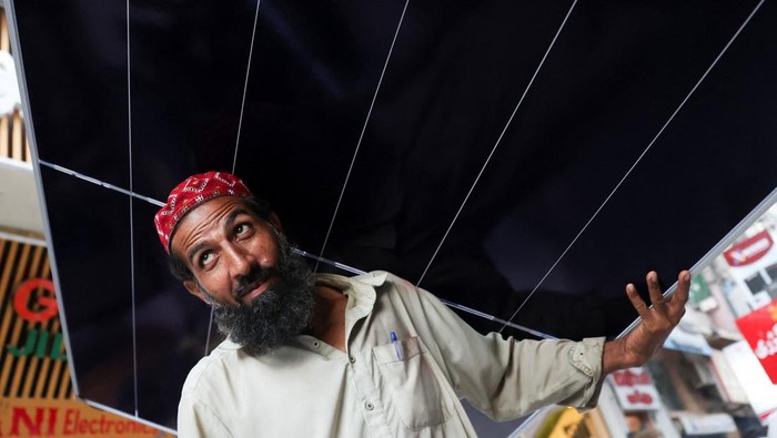 A worker carries a solar panel sheet on his head to load it on a vehicle outside a shop at an electronic items market in Karachi, Pakistan June 3, 2026. REUTERS/Akhtar Soomro