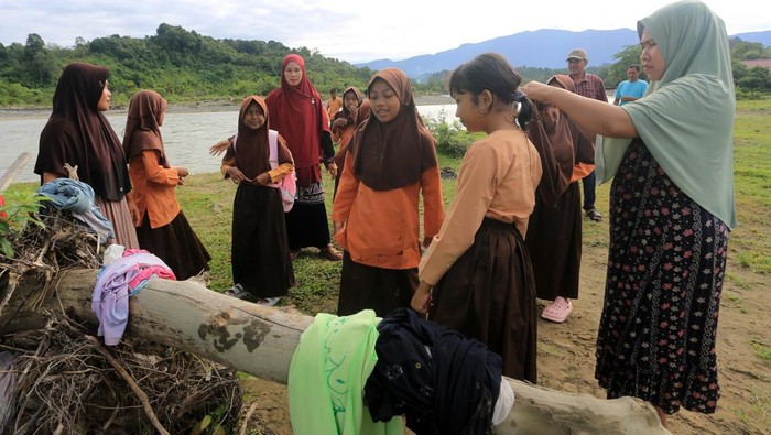 Orang tua siswa gendong anaknya di bahu saat melintasi sungai Meureubo untuk berangkat ke Sekolah Dasar Negeri (SDN) Alue Lhok dari Desa Canggai menuju ke Desa Jambak, Kecamatan Pante Ceureumen, Aceh Barat, Aceh, Jumat (5/6/2026). Sejak empat hari terakhir para siswa SDN Alue Lhok terpaksa mengarungi aliran sungai menuju kesekolah untuk mengikuti ujian kenaikan kelas guna mempersingkat jarak tempuh delapan kilometer karena jembatan gantung penghubung antar desa rusak pascabencana banjir bandang akhir November 2025 lalu tak kunjung diperbaiki. ANTARA FOTO/Syifa Yulinnas/YU