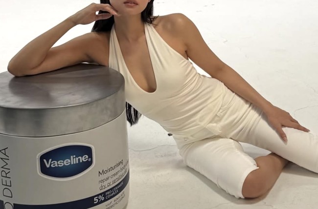 Jennie tampil mengenakan atasan halter-neck putih yang dipadukan dengan celana capri senada. Penyanyi berusia 30 tahun itu berpose santai sambil bersandar pada properti foto berbentuk produk Vaseline Pro Derma berukuran jumbo. Foto: dok. Instagram @@jennierubyjane