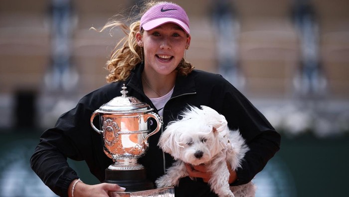 Mirra Andreeva berfoto bersama trofi French Open dan anjing kesayangannya.