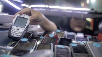 Penjual menggunakan telepon seluler lawas (ponsel fitur) di salah satu gerai di ITC Roxy Mas, Jakarta, kemarin. ANTARA FOTO/Rakha Raditya Yahya