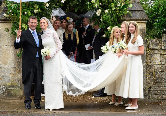 Harriet tampil dalam balutan gaun pengantin rancangan Emilia Wickstead. Gaun berenda berkerah tinggi itu dilengkapi ekor sepanjang tiga meter yang memberi kesan klasik dan anggun. Sementara Peter Phillips mengenakan setelan jas dengan vest biru dan dasi senada. Foto: Getty Images