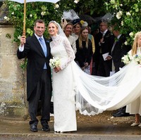 Harriet tampil dalam balutan gaun pengantin rancangan Emilia Wickstead. Gaun berenda berkerah tinggi itu dilengkapi ekor sepanjang tiga meter yang memberi kesan klasik dan anggun. Sementara Peter Phillips mengenakan setelan jas dengan vest biru dan dasi senada. Foto: Getty Images