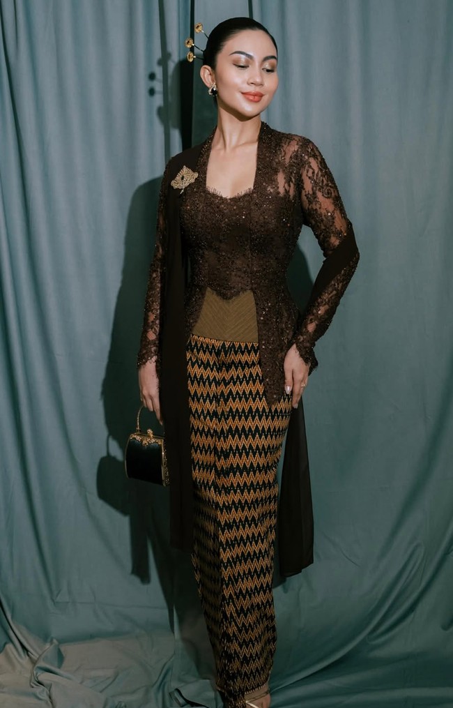 Kebaya tersebut dipadukan dengan kain batik bermotif geometris zig-zag berwarna cokelat dan hitam. Menariknya, kain yang dikenakan merupakan karya Tirto Tejo tahun 1965. Foto: Instagram/@arieltatum