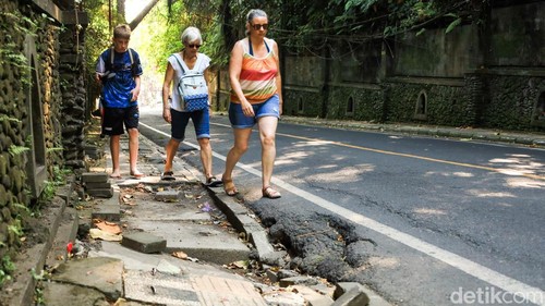 Beberapa turis harus berjalan dinaspal untuk menghindari kerusakan trotoar di di Jalan Raya Campuhan, Ubud, Gianyar, Senin (8/6/2026). (Aryo Mahendro/detikBali).