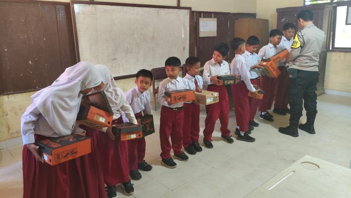 Polisi membagikan hadiah sepatu kepada siswa SD di Kuansing yang kurang mampu, Senin (8/6/2026).