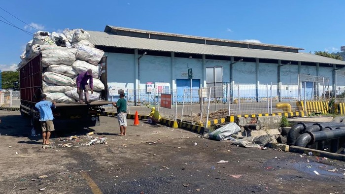 Truk pengganti tengah mengangkut rongsokan di lokasi truk terguling.
