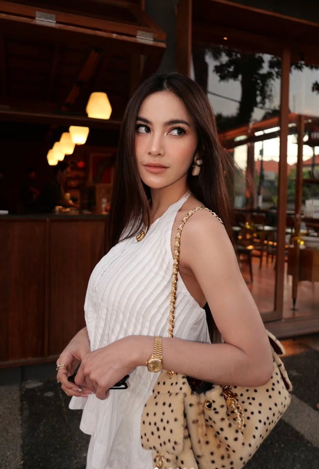 Mahalini memilih padukan atasan halter neck berwarna putih dengan aksesori bernuansa gold. Ia tampak mengenakan anting berukuran cukup besar berbentuk bulat dan persegi, kalung, cincin, serta jam tangan yang melingkar di pergelangan tangannya. Foto: Instagram/@mahaliniraharja
