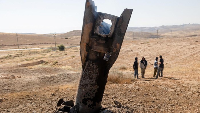 Israeli settlers stand next to part of a missile protruding from the ground, following strikes from Iran, in the central Israeli-occupied West Bank, June 8, 2026. REUTERS/Naama Stern ISRAEL OUT. NO COMMERCIAL OR EDITORIAL SALES IN ISRAEL     TPX IMAG