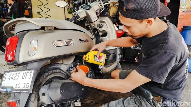 Montir mengganti oli sepeda motor di bengkel Padalarang.
