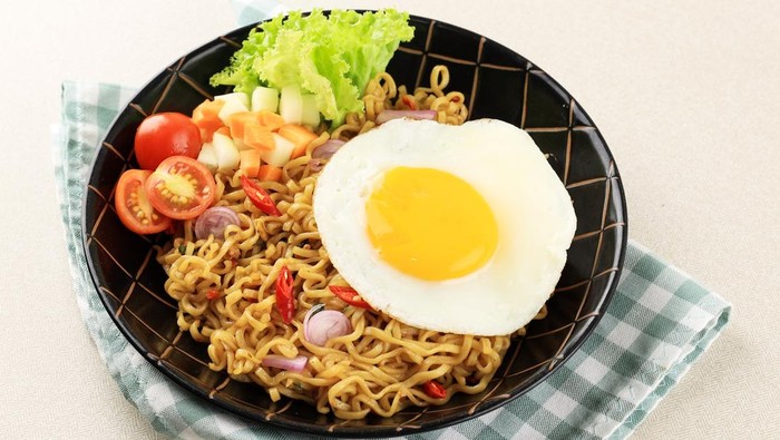 Indomie Goreng or Mie Goreng, Indonesian Popular Instant Noodle. Served with Sunny Side Egg, Tomato, Cucumber. Warmindo, Warkop, Ropang.Warmindo Mie Goreng dan Roti Bakar