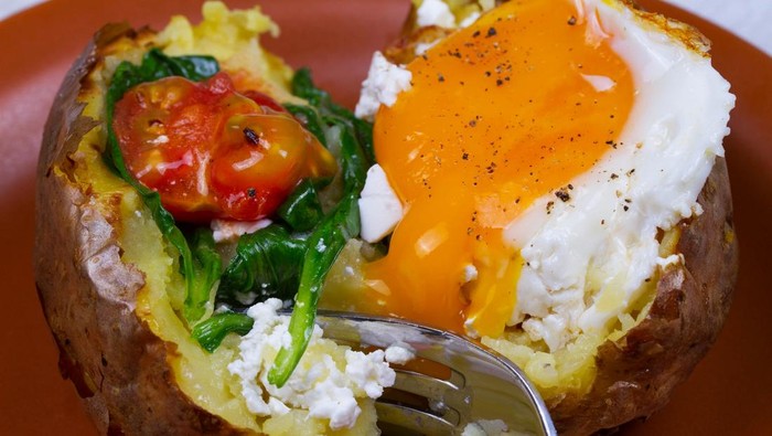 Baked potato with fried egg, feta, spinach and tomato cherry